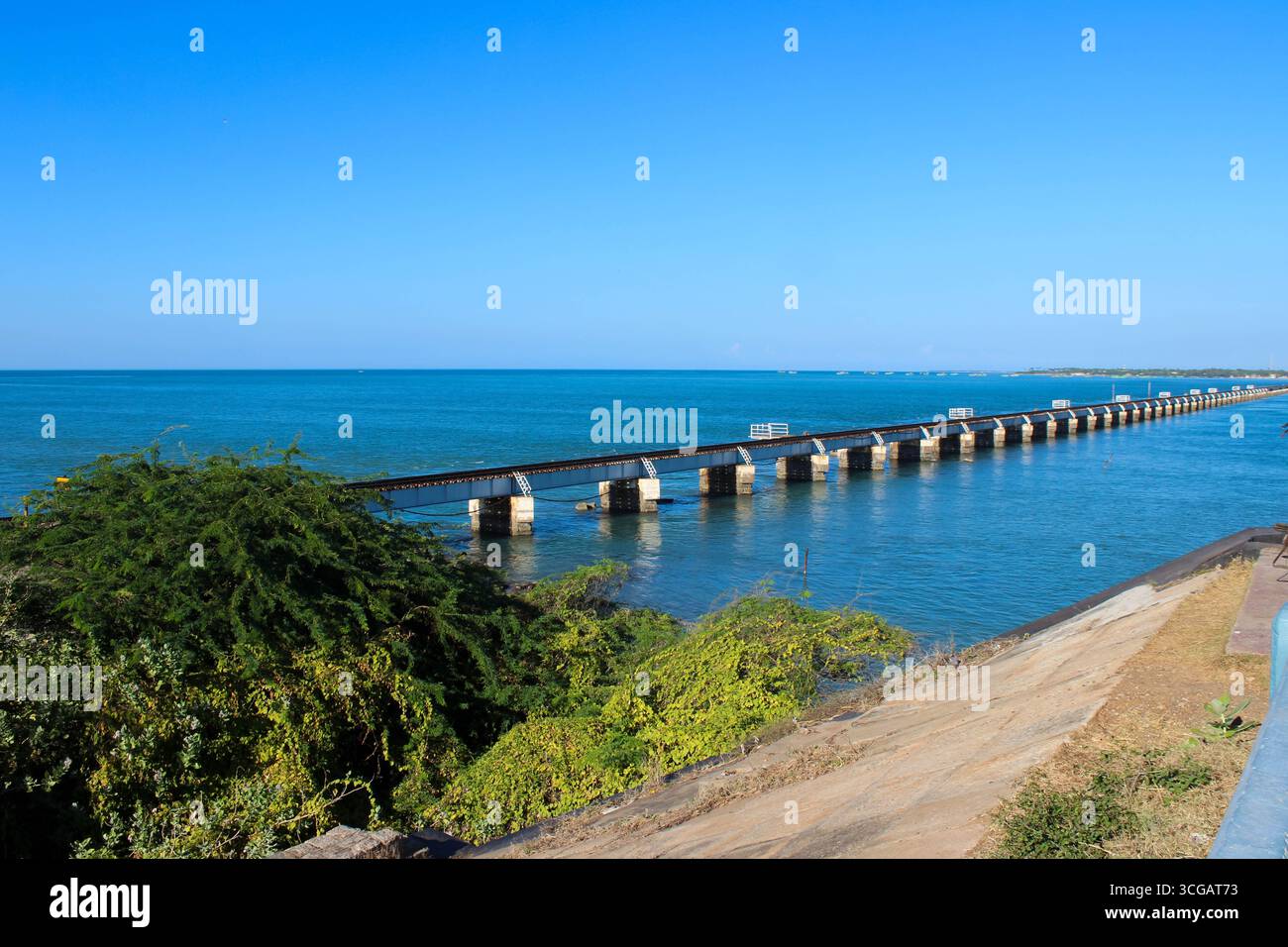 Auf dem Weg nach Dhanuschkodi führt eine enge Straße, die vom Meer flankiert wird, zu den eindringlichen Ruinen der Geisterstadt, die einen atemberaubenden Blick auf das Meer und die Geschichte bietet. Stockfoto