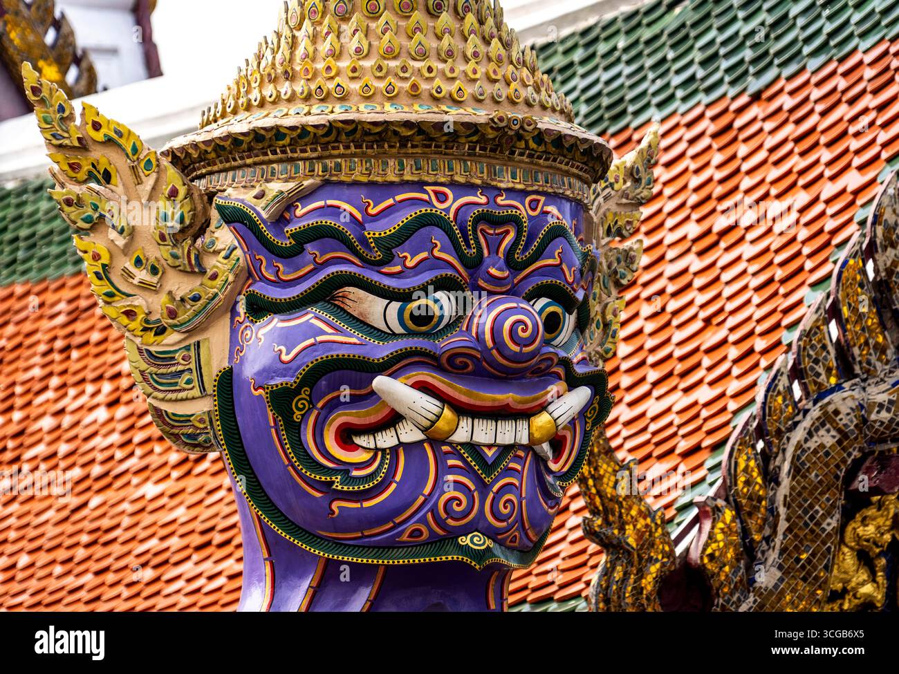 Eine farbenfrohe Statue einer mythischen Kreatur mit komplizierten Details vor dem Hintergrund traditioneller thailändischer Architektur Stockfoto