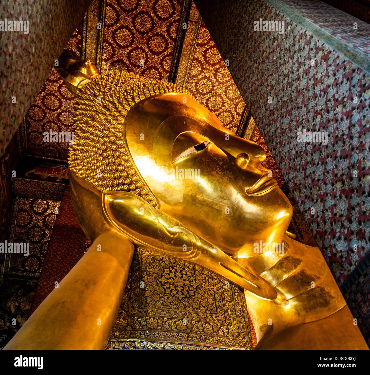 Eine große goldene Buddha-Statue aus nächster Nähe mit komplizierten Details und Texturen vor einem reich verzierten Hintergrund mit traditionellem Hintergrund Stockfoto