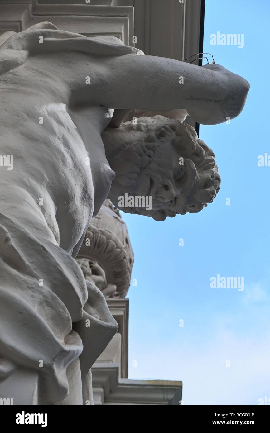 Detaillierte Ansicht einer muskulösen männlichen Figur aus weißem Marmor oder Gips, möglicherweise eines Atlas, der Gewicht auf dem Kopf trägt, mit blauem Himmel und Arch Stockfoto