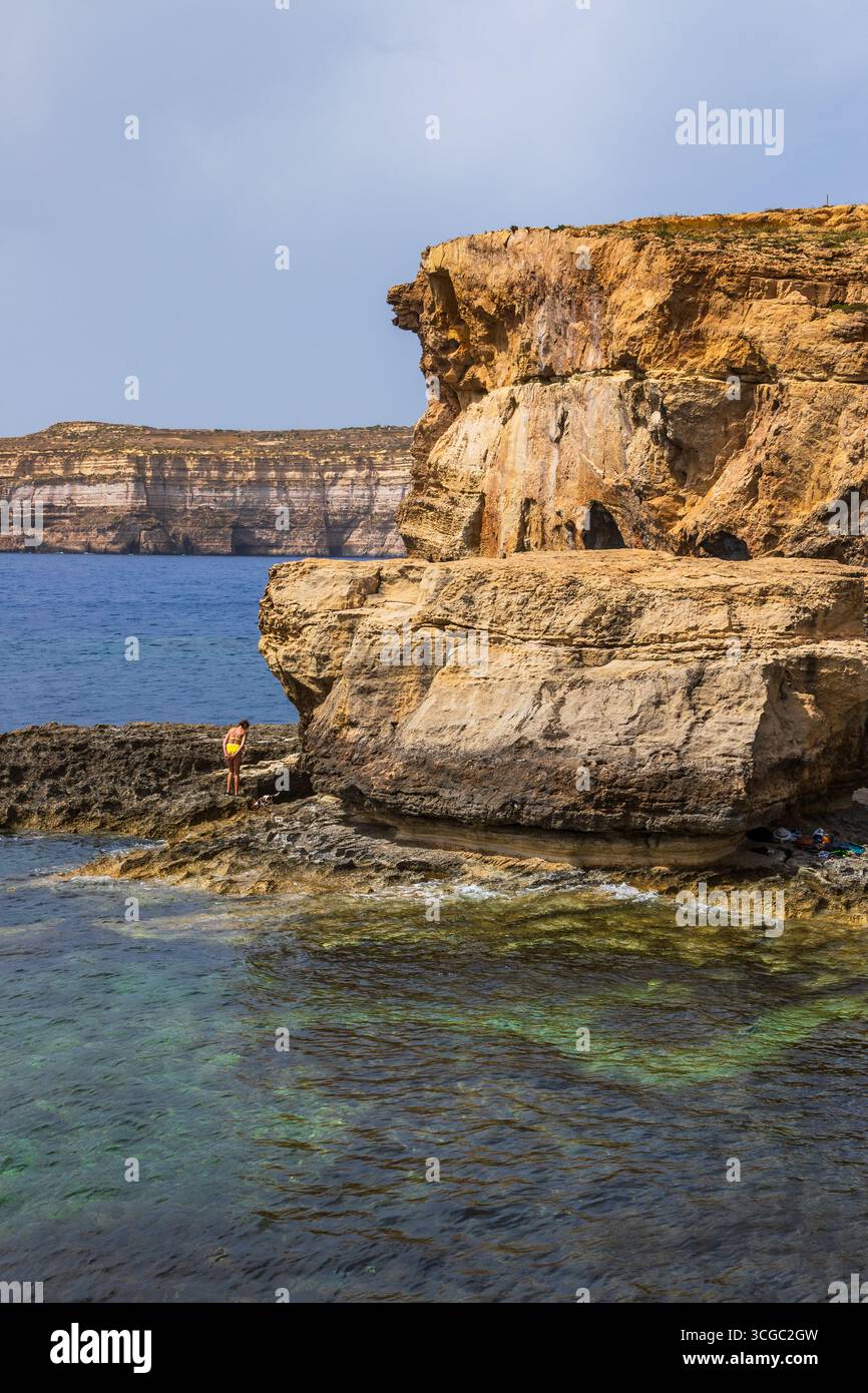 Gozo, Malta – 23. Juni 2021: Touristen erkunden zerklüftete Kalksteinklippen mit Blick auf das Mittelmeer. Stockfoto