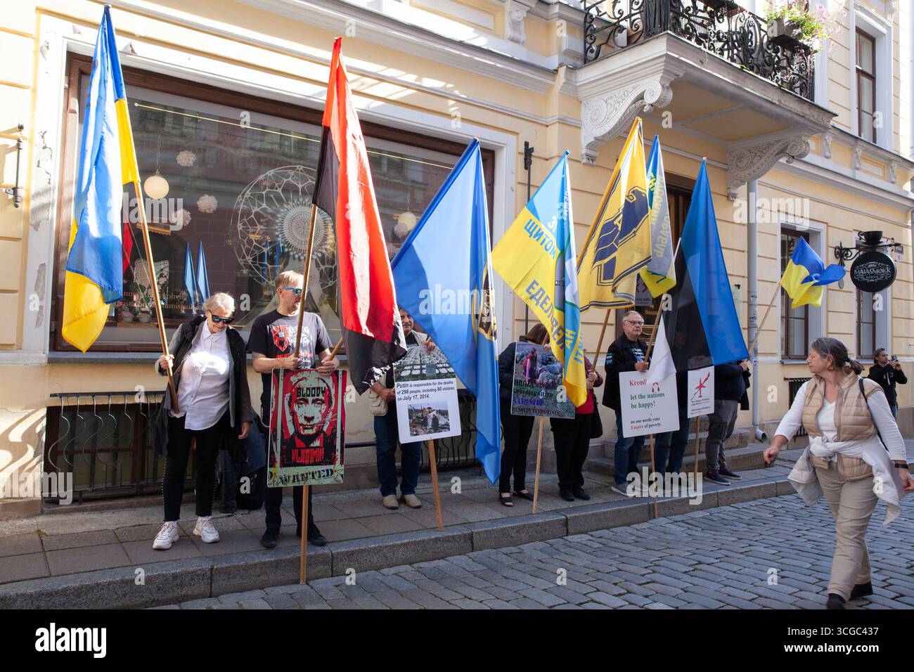 Tallinn, Estland, 27. August 2025: Vor der russischen Botschaft in Estlands Hauptstadt findet wöchentlich ein Protest gegen die Regierungspolitik statt. Die Demonstranten kritisierten Russlands Invasion in der Ukraine und Georgien und seine internen Durchgreifungen der Redefreiheit. Sie riefen auf Russisch Slogans, die den Botschaftsmitarbeitern direkt gegenüber einer engen Kopfsteinpflasterstraße in der Stadt des UNESCO-Weltkulturerbes deutlich zu hören gewesen sein müssen. Die rote und schwarze Version der ukrainischen Flagge repräsentiert die ukrainische Aufständische Armee (UPA). Schutzbarrieren außerhalb der Botschaft sind in Plakaten und Protesterklärungen verdeckt Stockfoto