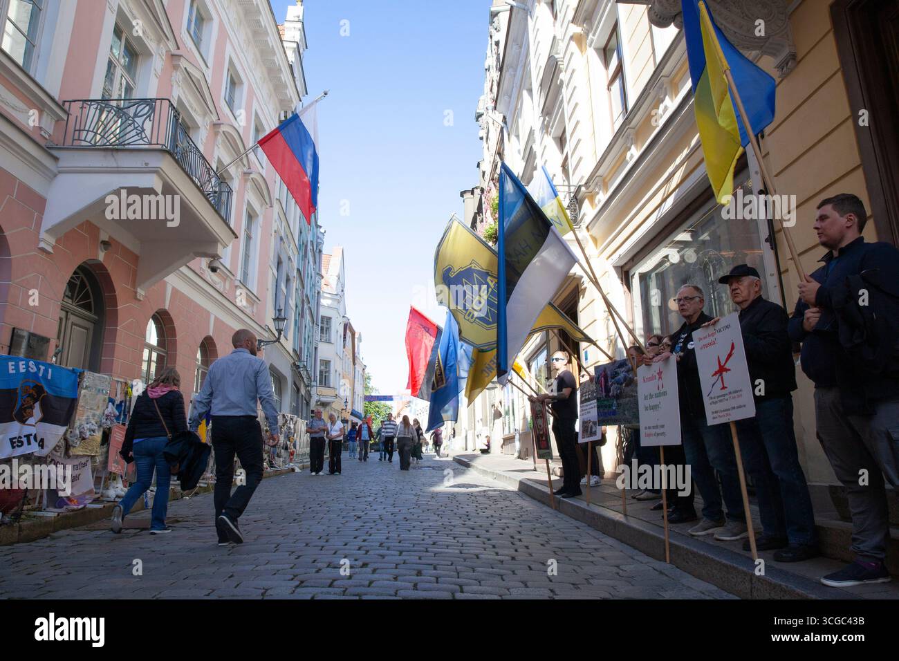 Tallinn, Estland, 27. August 2025: Vor der russischen Botschaft in Estlands Hauptstadt findet wöchentlich ein Protest gegen die Regierungspolitik statt. Die Demonstranten kritisierten Russlands Invasion in der Ukraine und Georgien und seine internen Durchgreifungen der Redefreiheit. Sie riefen auf Russisch Slogans, die den Botschaftsmitarbeitern direkt gegenüber einer engen Kopfsteinpflasterstraße in der Stadt des UNESCO-Weltkulturerbes deutlich zu hören gewesen sein müssen. Die rote und schwarze Version der ukrainischen Flagge repräsentiert die ukrainische Aufständische Armee (UPA). Schutzbarrieren außerhalb der Botschaft sind in Plakaten und Protesterklärungen verdeckt Stockfoto