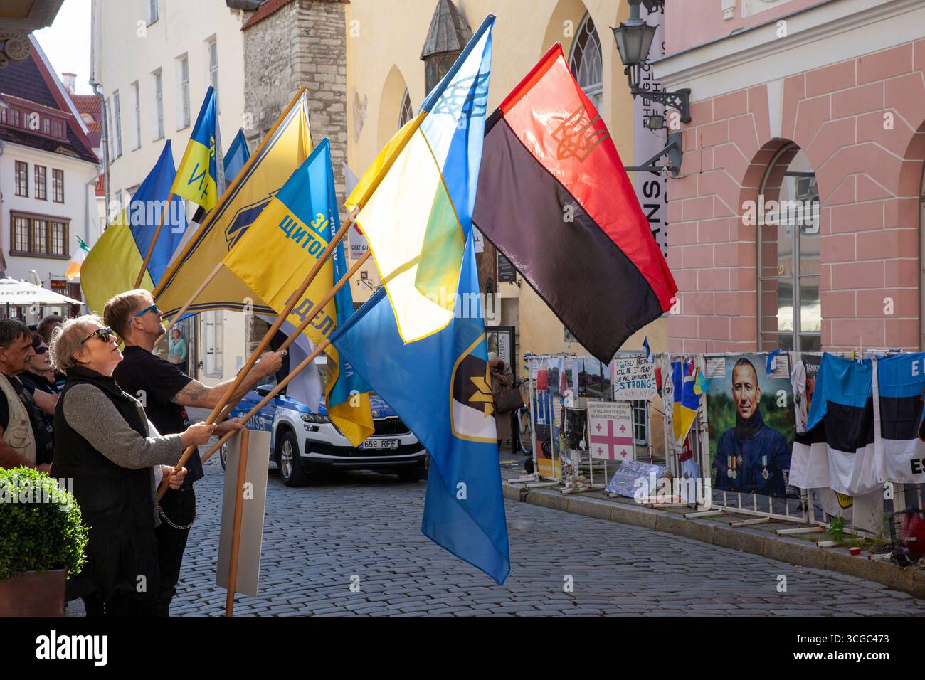 Tallinn, Estland, 27. August 2025: Vor der russischen Botschaft in Estlands Hauptstadt findet wöchentlich ein Protest gegen die Regierungspolitik statt. Die Demonstranten kritisierten Russlands Invasion in der Ukraine und Georgien und seine internen Durchgreifungen der Redefreiheit. Sie riefen auf Russisch Slogans, die den Botschaftsmitarbeitern direkt gegenüber einer engen Kopfsteinpflasterstraße in der Stadt des UNESCO-Weltkulturerbes deutlich zu hören gewesen sein müssen. Die rote und schwarze Version der ukrainischen Flagge repräsentiert die ukrainische Aufständische Armee (UPA). Schutzbarrieren außerhalb der Botschaft sind in Plakaten und Protesterklärungen verdeckt Stockfoto