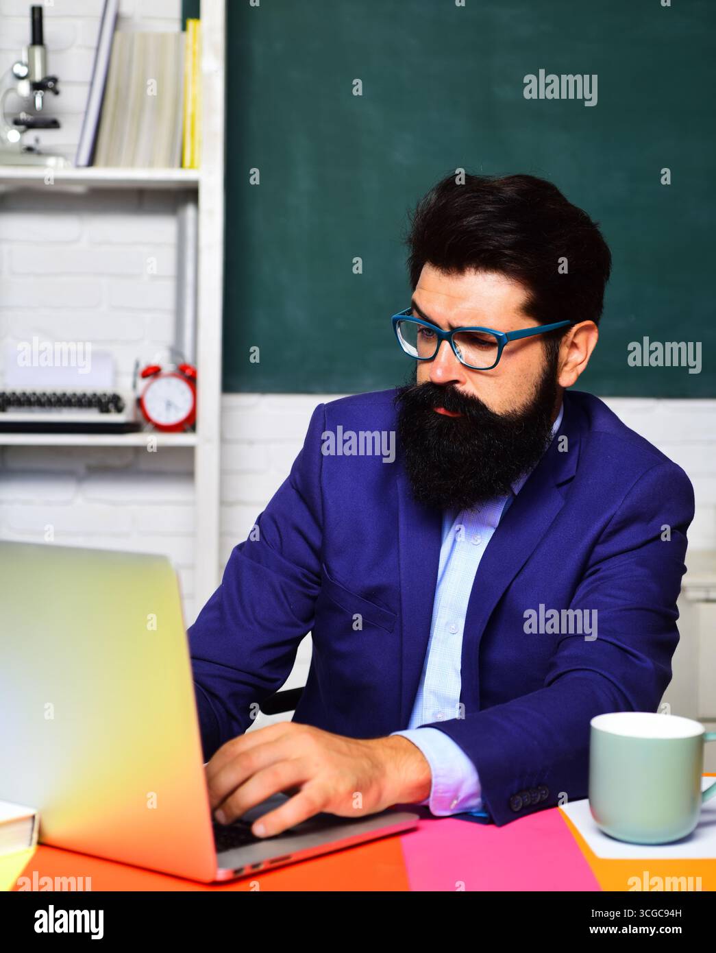 Nachdenklicher Student in Brille, der sich auf die Prüfung oder Prüfung an der Universität vorbereitet. Lernen, Bildung. Männlicher Schüler macht Notizen im Laptop. Ernsthafter Schullehrer Stockfoto