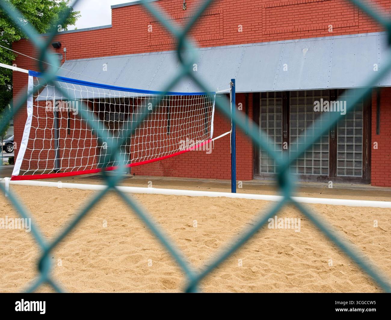Blick auf das Sandvolleyballfeld durch den grünen Maschendrahtzaun Stockfoto