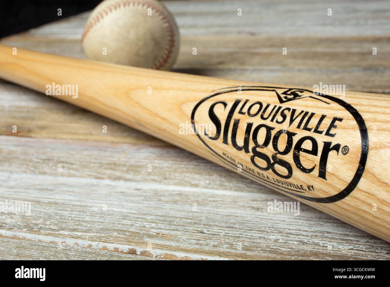 Los Angeles, Kalifornien, USA - 25.02.2020: Nahaufnahme einer Louisville Slugger Holzschlägerin mit einem verwitterten Baseball auf einer Holzoberfläche. Stockfoto