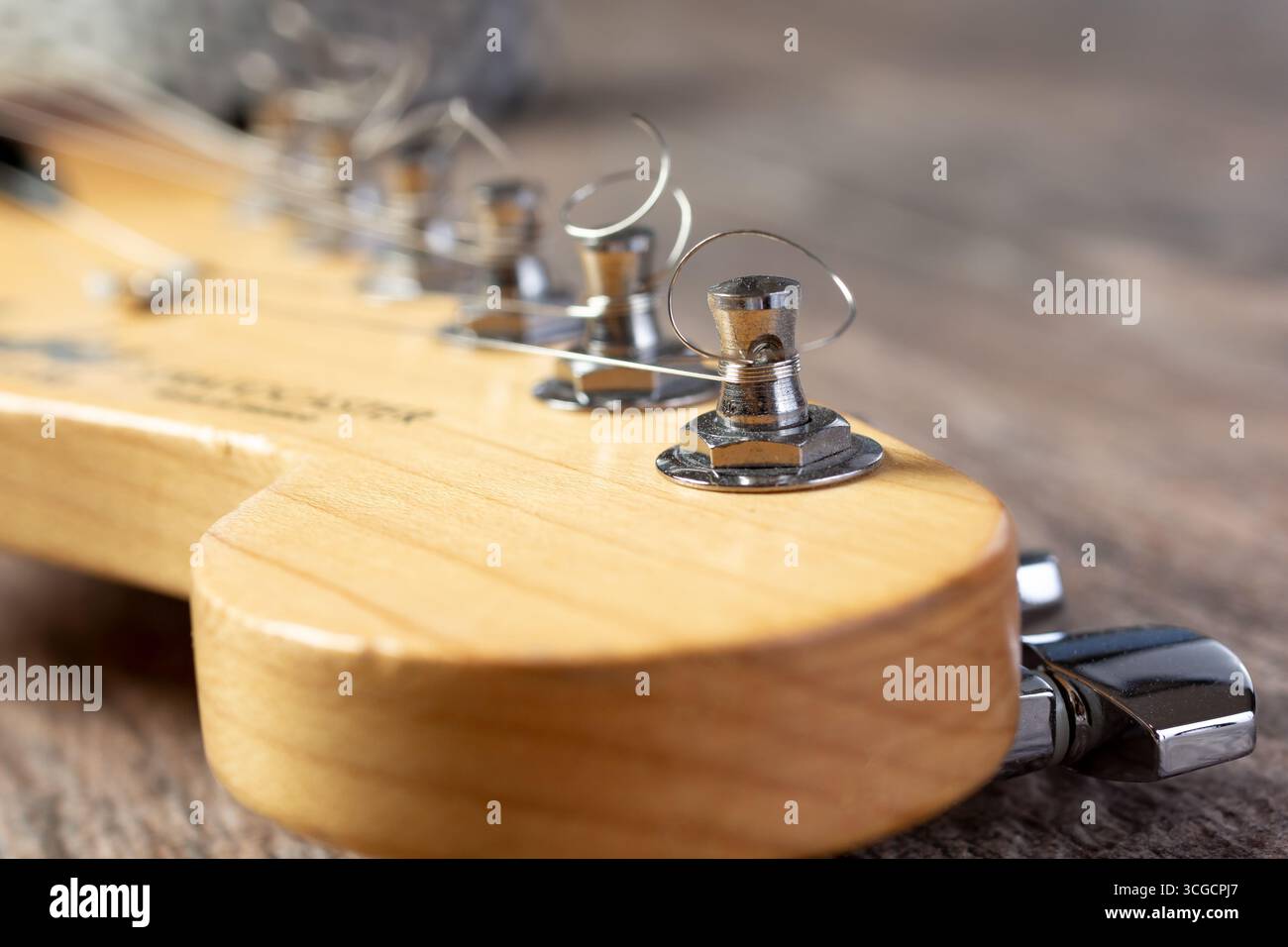 Eine Nahaufnahme der Saitenstifte und Stimmgeräte auf dem Kopf oder Kopfstock einer elektrischen Gitarre. Stockfoto