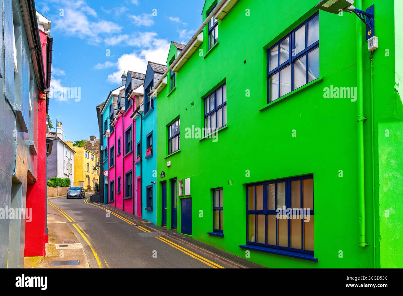 Eine farbenfrohe Wohnstraße mit rosa, türkisfarbenen, roten und lindgrünen Häusern in der Küstenstadt Kinsale, County Cork, Irland. Stockfoto