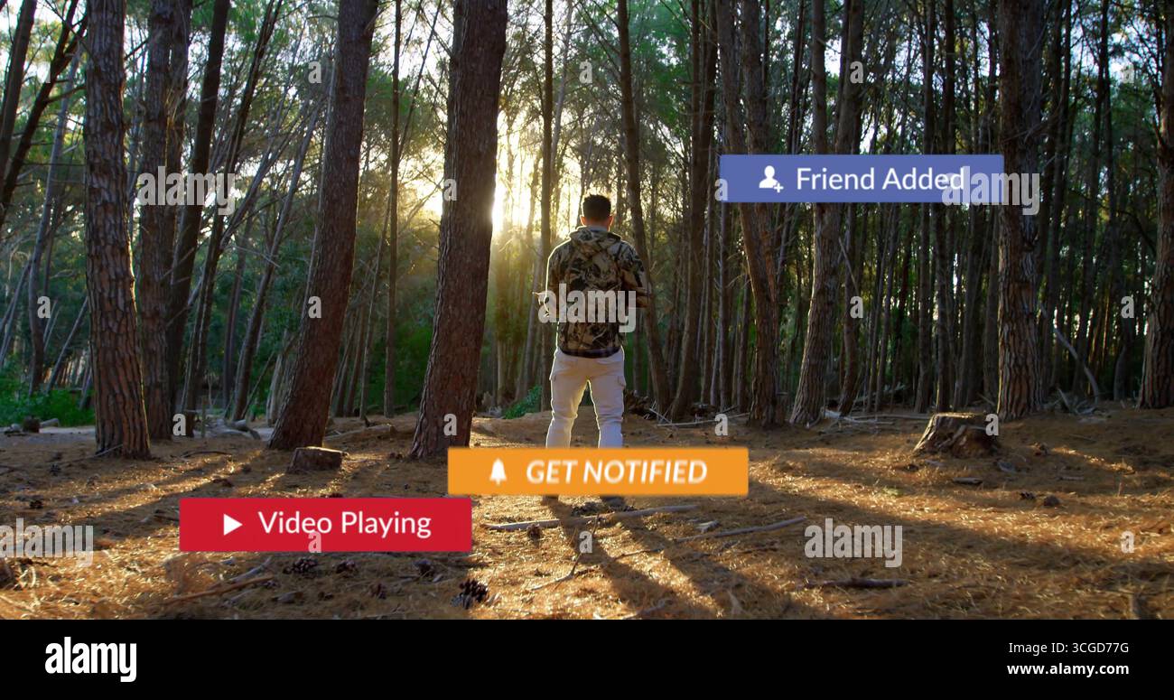 Anzeige von Benachrichtigungsüberlagerungen, Mann im Tarnhemd, der Smartphone an der Kiefernwaldlichtung hält Stockfoto