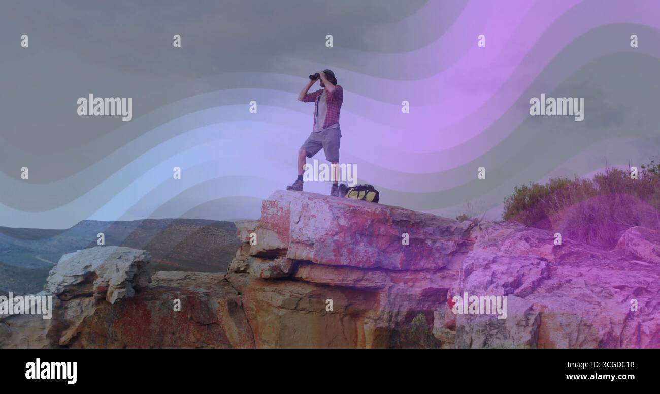 Einsamer Wanderer mit Stiefeln mit einem Fernglas scannen, während er auf Sandsteinklippe steht, mit Rucksack Stockfoto