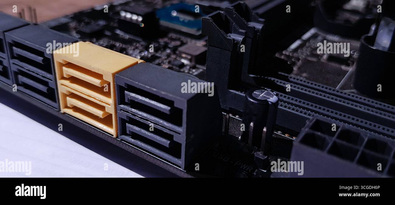 Eine detaillierte Nahaufnahme eines PC-Mainboards mit mehreren SATA III-Ports, darunter einem gelben Anschluss. Hebt die wichtigsten PC-Komponenten hervor Stockfoto
