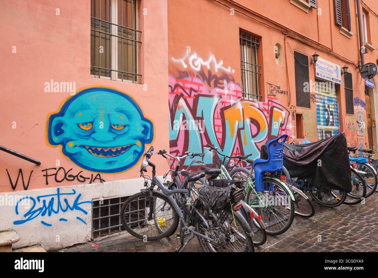 Typische Ansicht einer Wand in der Nähe eines Fahrradträgers, bedeckt mit Sprühfarben. Street Art, Graffiti in Bologna, Italien. Stockfoto
