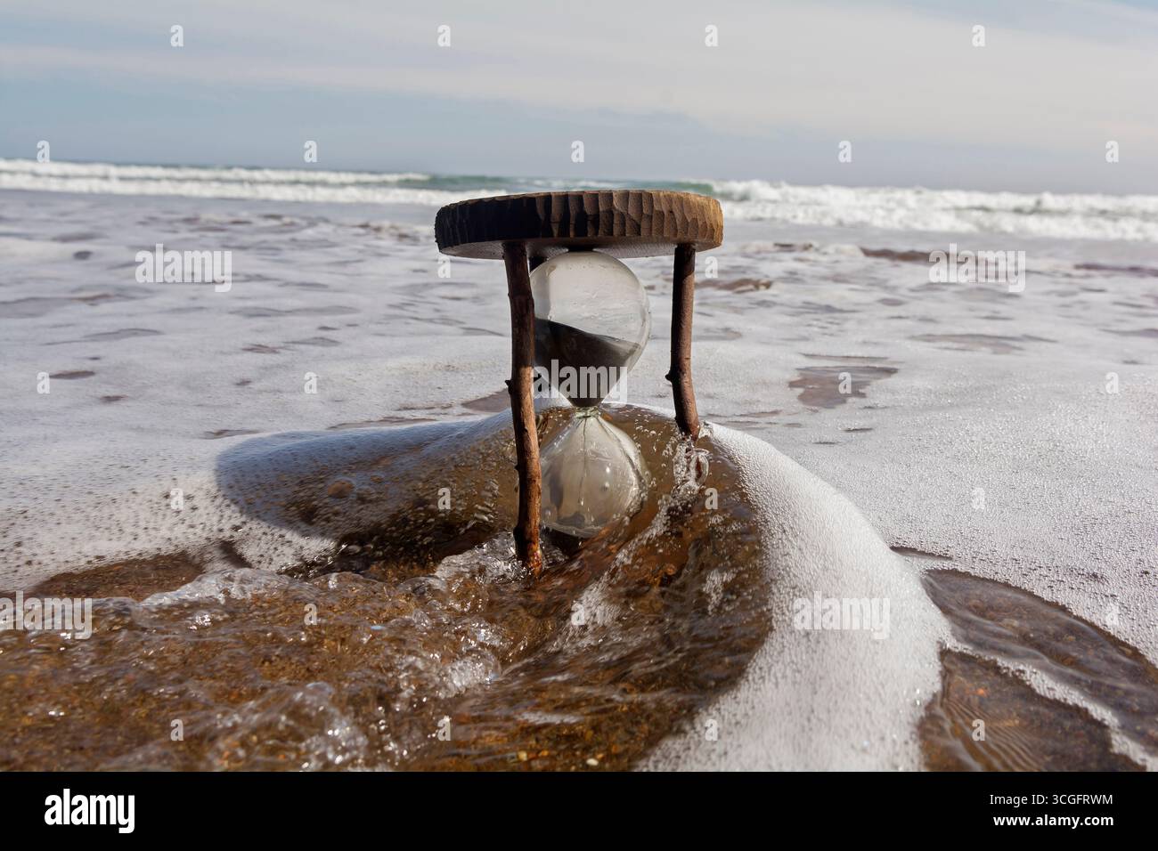 Sanduhr im Meer zwischen den Wellen Stockfoto