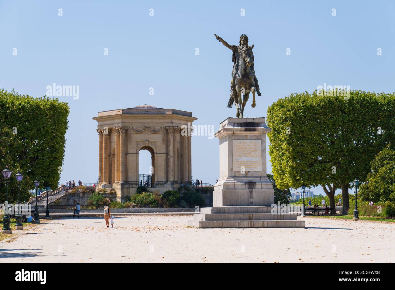 Montpellier, Frankreich - 7. August 2025: Place du Peyrou mit der Statue Ludwigs XIV. Und dem Wasserturm von Peyrou im Hintergrund, Leute gehen vorbei Stockfoto