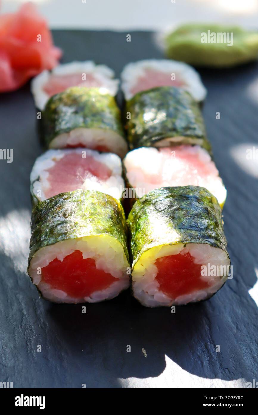 Traditionelle Thunfisch-uzumaki-Stücke auf einem dunklen Teller serviert mit Ingwer und Wasabi. Naturlichtfotografie Stockfoto