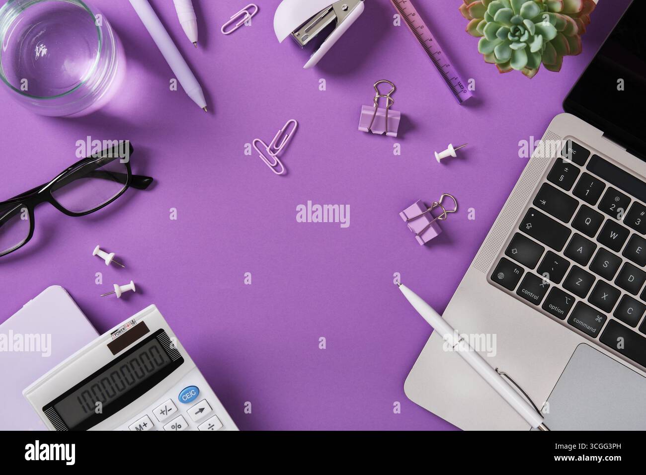 Schreibtisch mit Laptop, Stift, Hefter, Brille, Büroklammer, und Taschenrechner auf violettem Hintergrund. Platzieren für Ihren Text. Stockfoto