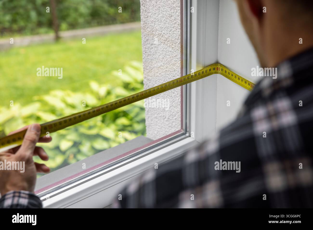 Mann misst den weißen Kunststoffrahmen für den Austausch Stockfoto