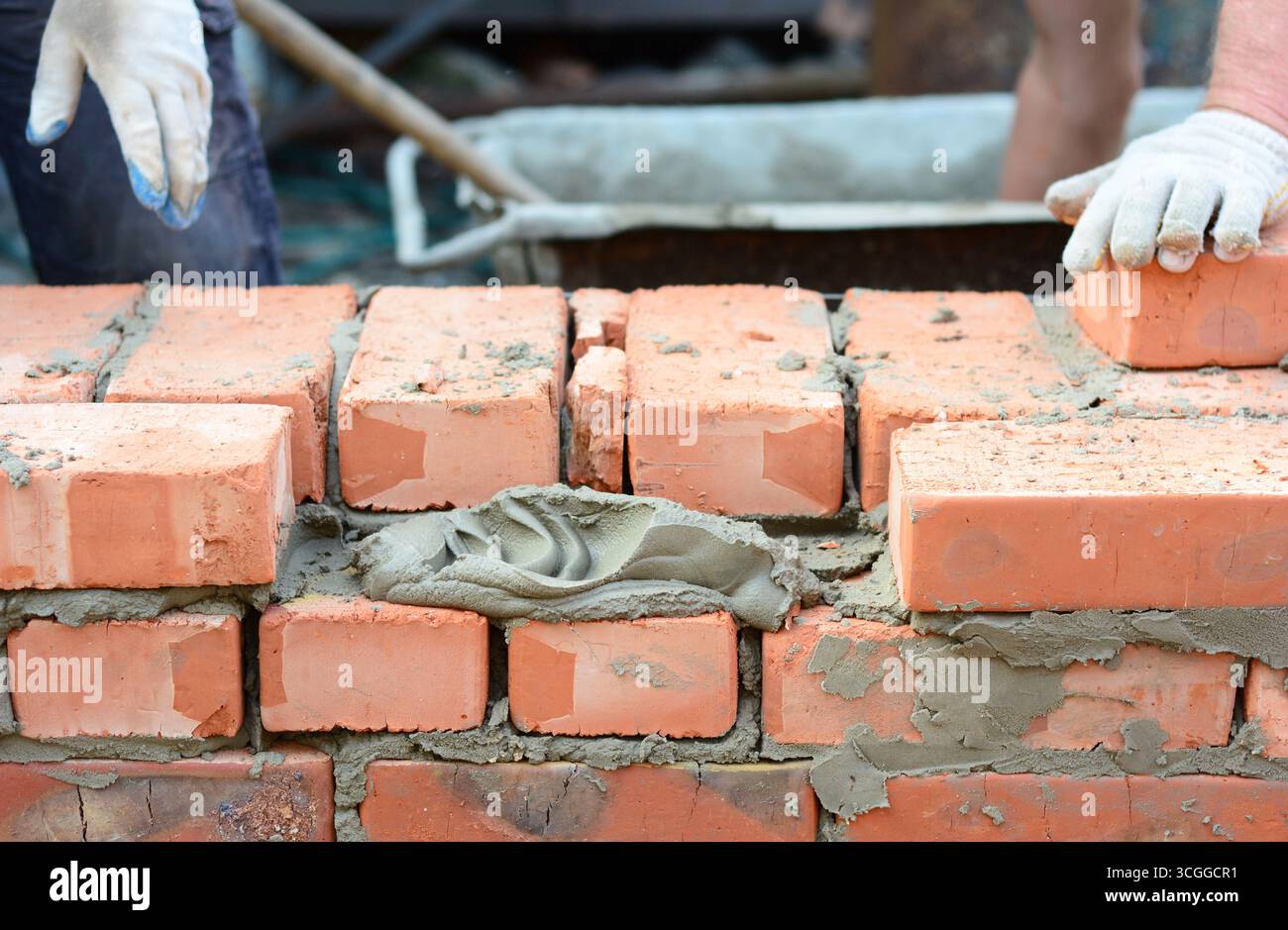 Maurerkonzept. Rote Ziegelwand mit Zementmörtel für die Mauerverlegung. Stockfoto