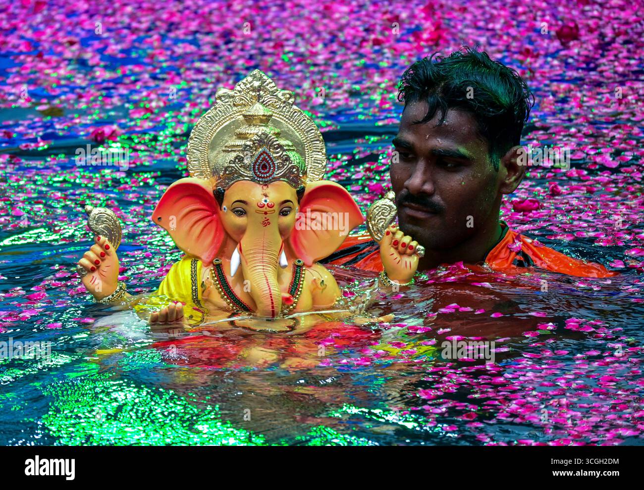 Ein Freiwilliger trägt ein Idol der hinduistischen Gottheit Ganesha, um während des Ganesh Chaturthi Festivals in Mumbai in künstliche Teiche einzutauchen. Stockfoto