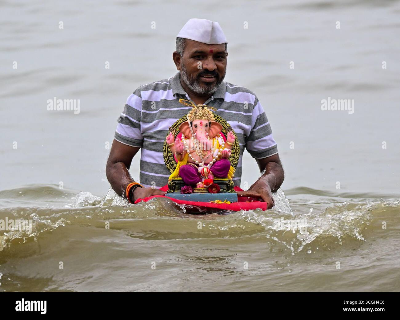 Ein Anhänger trägt ein Idol der hinduistischen Gottheit Ganesha, um während des Ganesh Chaturthi Festivals in Indien Mumbai.in in das Arabische Meer einzutauchen. Stockfoto