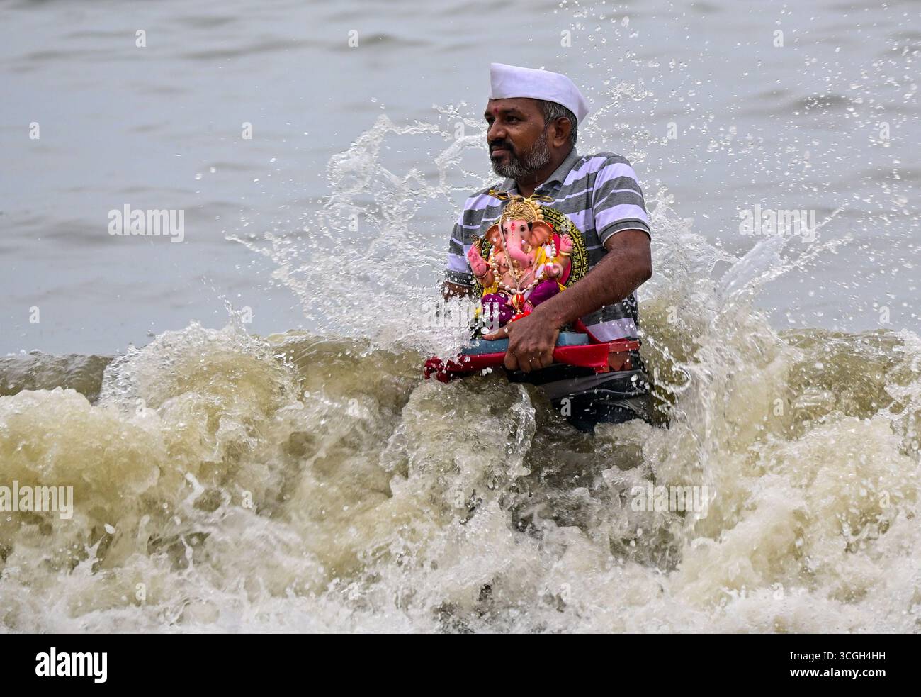 Ein Anhänger trägt ein Idol der hinduistischen Gottheit Ganesha, um während des Ganesh Chaturthi Festivals in Indien Mumbai.in in das Arabische Meer einzutauchen. Stockfoto