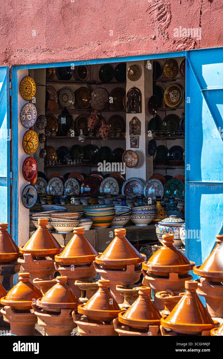 Traditionelles marokkanisches Töpfergeschäft mit farbenfrohen Keramikplatten und Tagine-Töpfen im Freien unter hellem Sonnenlicht in Marokko. Stockfoto