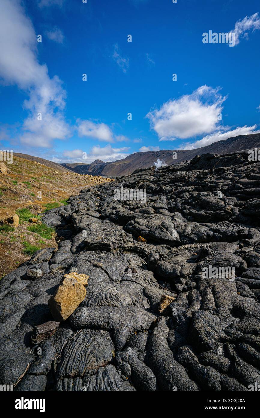 Islands vulkanische Landschaft entfaltet sich mit endlosen schwarzen Lavafeldern unter einem leuchtend blauen Himmel und fängt den rohen Geist des Landes aus Feuer und Eis ein Stockfoto