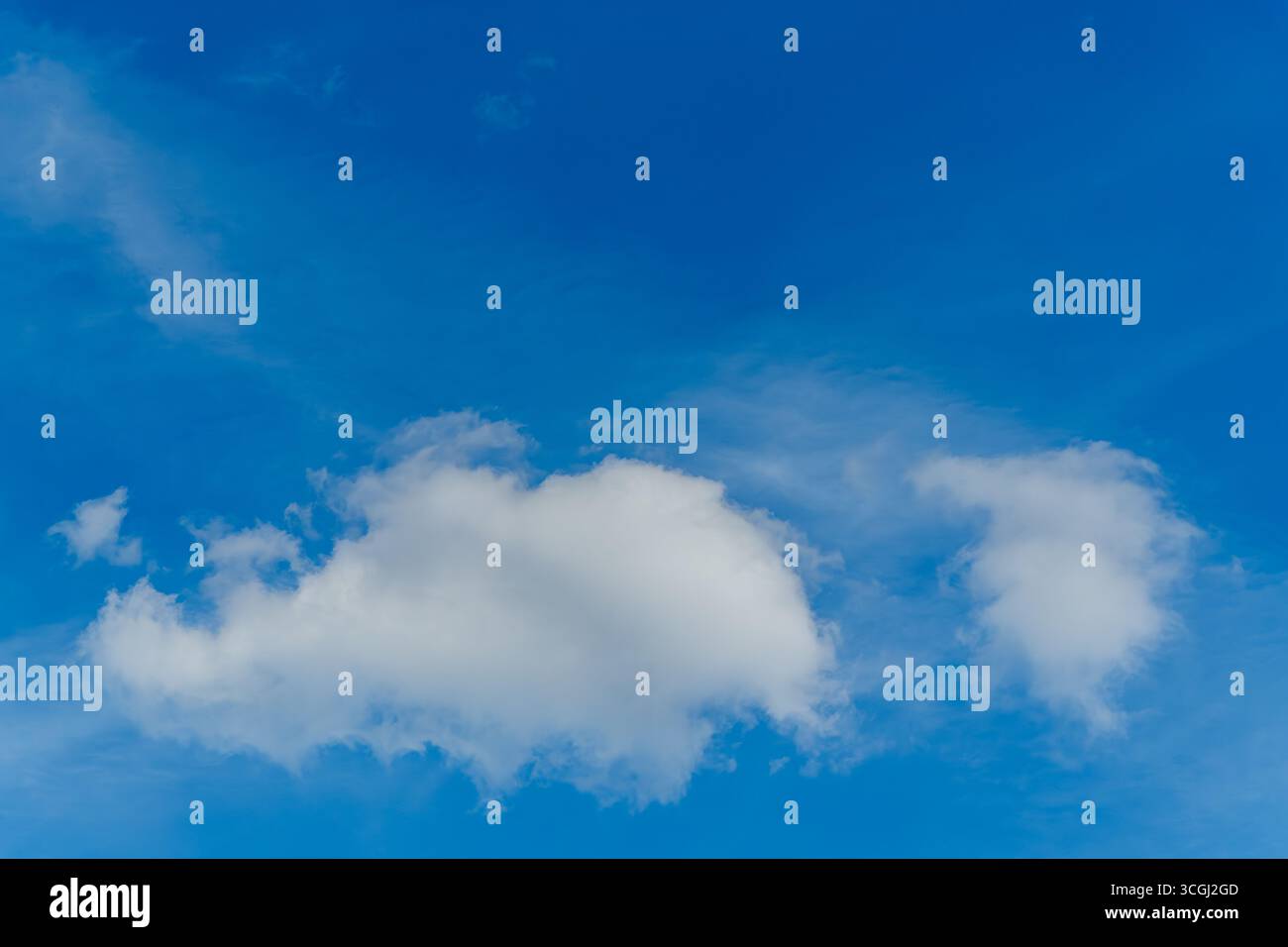 Eine helle weiße Cumulus-Wolke gleitet friedlich über einen klaren blauen Himmel. Seine weichen Konturen und die isolierte Form erinnern an Leichtigkeit, Freiheit und Ruhe. Stockfoto