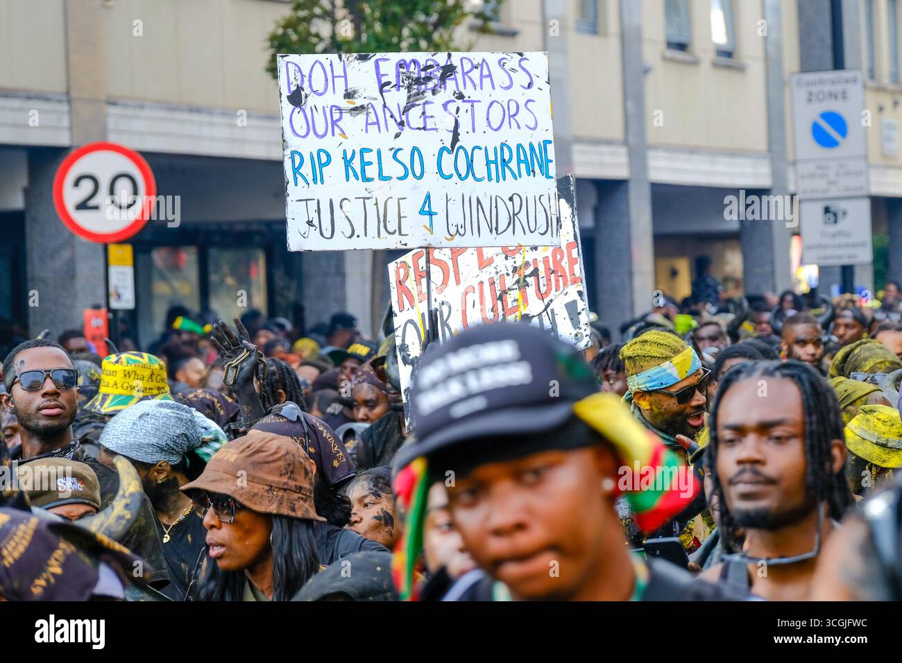 Ein Jab-Jab-Teilnehmer hält ein Schild hoch, das an die jüngsten Kämpfe der karibischen Gemeinschaft in Großbritannien erinnert. Stockfoto