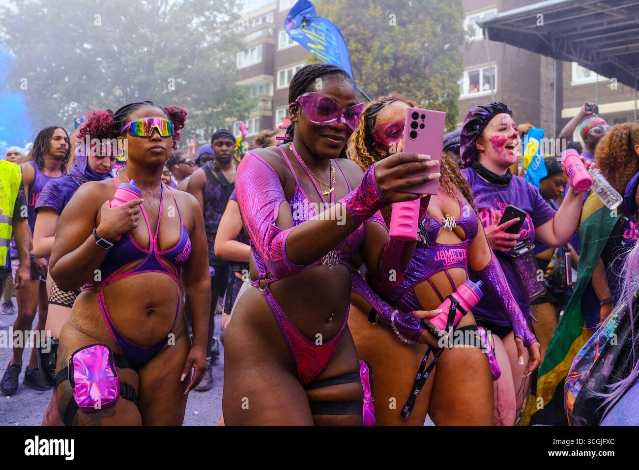 Die Nachtschwärmer passieren die Urteilsstelle am Notting Hill Carnival und werden ermutigt, ihre Socken abzutanzen, während purpurfarbenes Pulver in die Luft gepumpt wird. Stockfoto