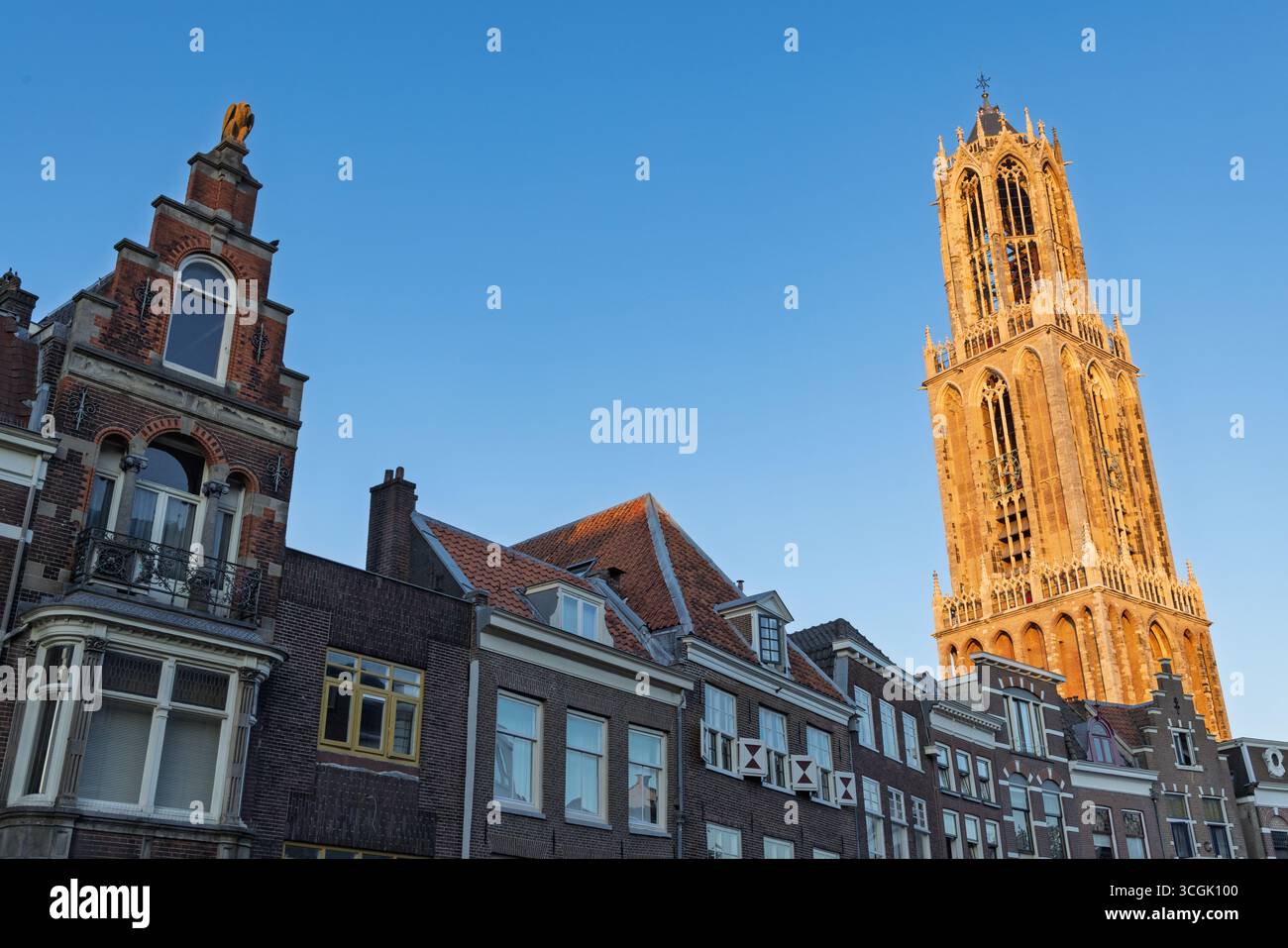 Ein malerischer Blick auf den Domturm „domtoren“ in Utrecht, majestätisch hinter einer bezaubernden Sammlung traditioneller niederländischer Häuser mit unverwechselbaren Stockfoto