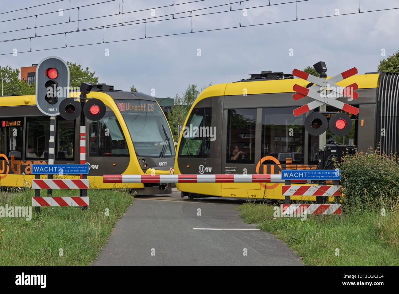 Schranken, Stadtverkehr, Pendlerzug, Übergangstor, Warnung beim Überschreiten, niederländisch, niederländische Stadt, Elektrozug, elektrische Straßenbahn, Elektrotransport. Stockfoto