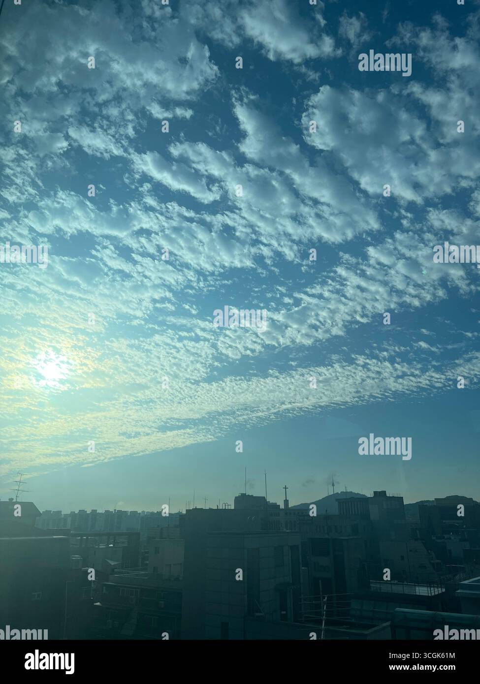 Altocumulus bewölkt sich über dem Gangnam-Viertel von Seoul, und das Sonnenlicht scheint sanft durch die Wolken. - Smartphone-aufgenommenes Stockfoto
