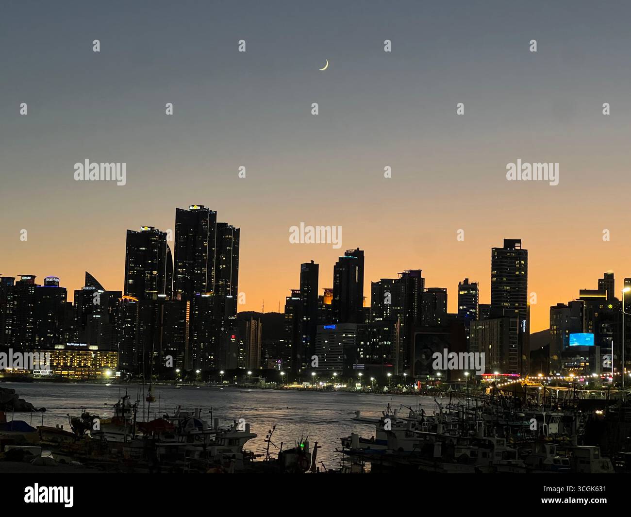 Nächtlicher Blick auf die Skyline von Haeundae in Busan, Südkorea, mit den Lichtern der Stadt über dem Meer, von Mipo aus gesehen. - Smartphone-aufgenommenes Stockfoto