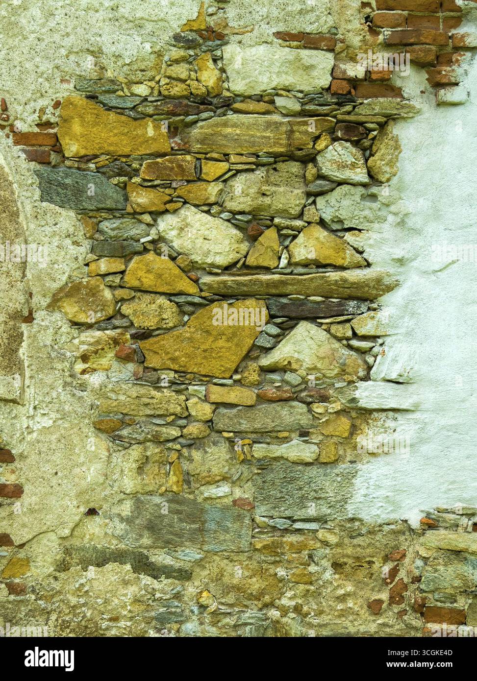 Verwitterte Steinmauer mit gelben und grauen Steinen, die eine raue, rustikale Textur der Steiermark Österreich zeigt Stockfoto