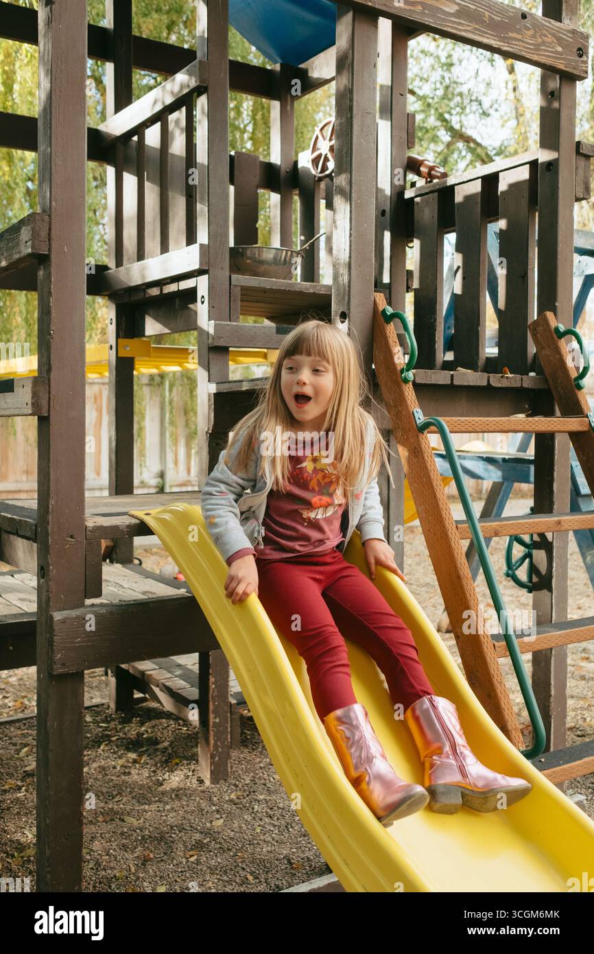 Vorschulmädchen genießt im Herbst eine Rutsche auf dem Spielplatz Stockfoto