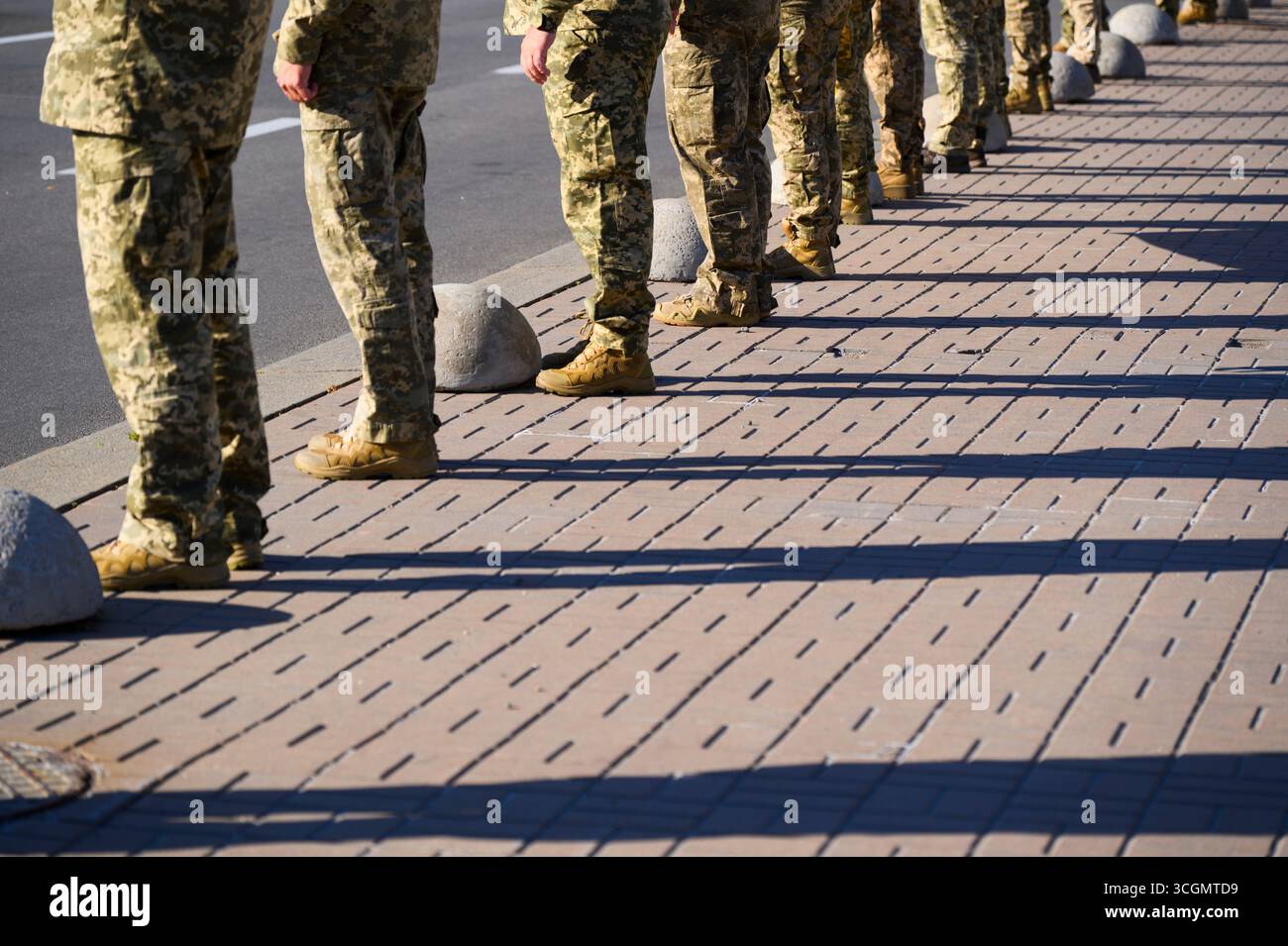 Kiew, Ukraine - 29. August 2025: Ukrainische Soldaten in Tarnuniformen stehen in Formation und werfen während der militärischen Gedenkveranstaltung lange Schatten auf den Bürgersteig Stockfoto