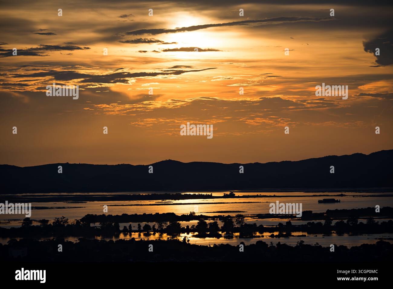Ayeyarwady River Golden Sunset View vom Mandalay Hill Mandalay Myanmar // MANDALAY, Myanmar – Ein goldener Sonnenuntergang beleuchtet den Ayeyarwady River (auch bekannt als Irrawaddy River oder Ayeyarwaddy River), vom Gipfel des Mandalay Hill aus gesehen. Mandalay Hill, der 230 Meter (750 Fuß) über der Stadt ragt, ist ein bedeutender Wallfahrtsort und beliebter Aussichtspunkt mit Panoramablick auf Mandalay und seine Umgebung. Der Ayeyarwady River ist Myanmars längster Fluss und fließt etwa 2.170 Kilometer (1.350 Meilen) von Norden nach Süden. Es ist die wichtigste kommerzielle Wasserstraße des Landes, vita Stockfoto