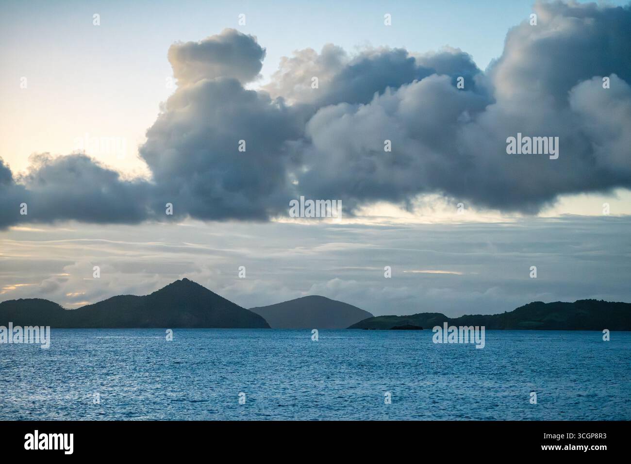 Inseln im Karibischen Meer in der Nähe von St. John US Jungferninseln in der Abenddämmerung // St. JOHN, USVI — das Karibische Meer ist mit Inseln in der Ferne unter einem Himmel zu sehen, der am frühen Abend mit dramatischen Wolken gefüllt ist. Die US-amerikanischen Jungferninseln, ein Territorium der Vereinigten Staaten, befinden sich im Nordosten der Karibik. St. John ist die kleinste der drei wichtigsten amerikanischen Jungferninseln. Stockfoto