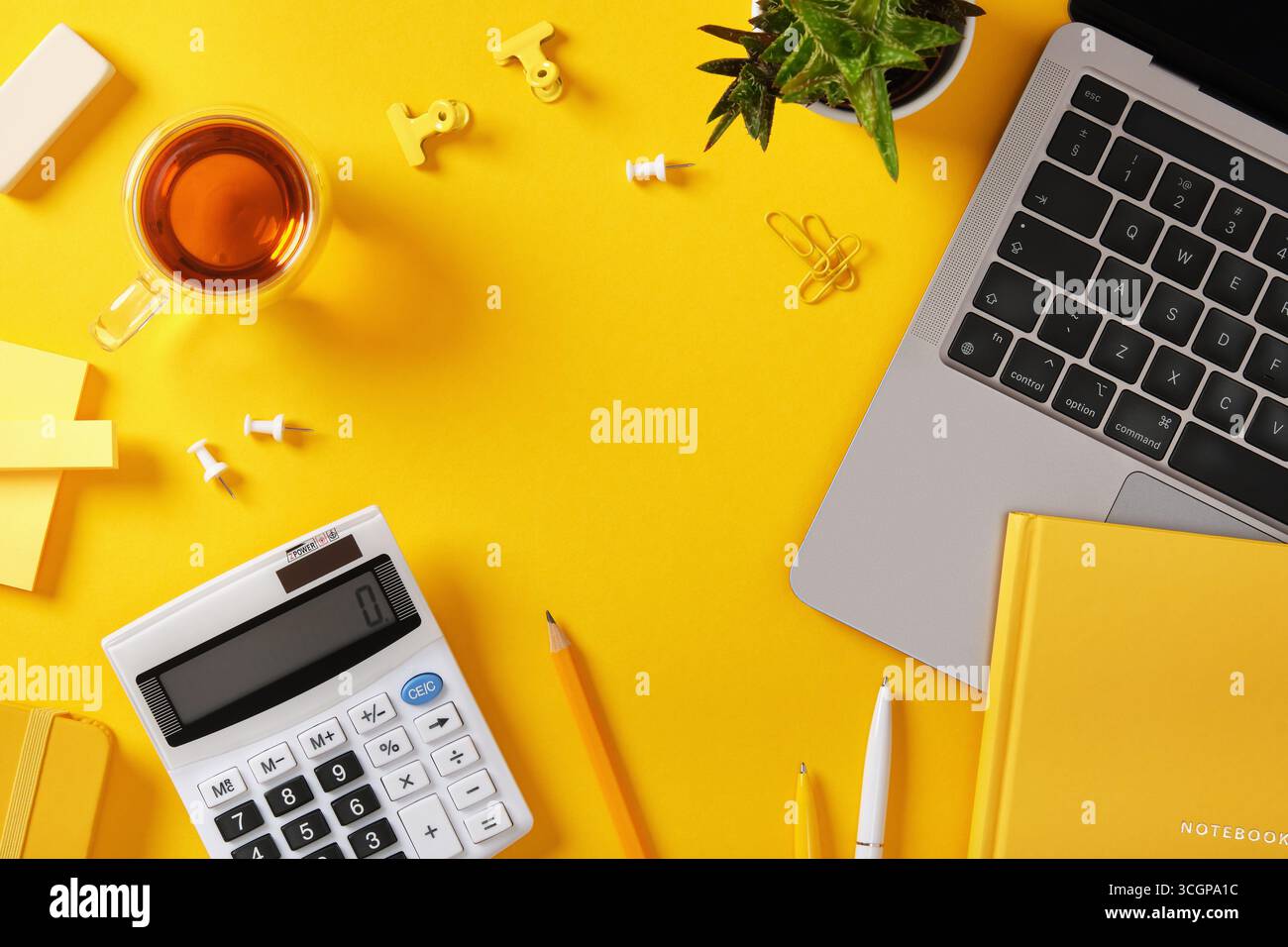 Gelber Schreibtisch mit Laptop, Stift, Büroklammer, Taschenrechner und Notebook. Platzieren für Ihren Text. Stockfoto