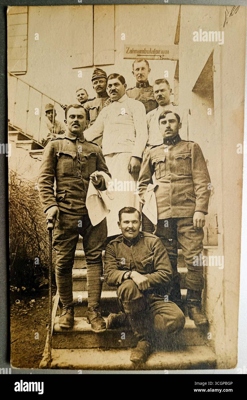Militärangehörige der österreichisch-ungarischen Armee während des Ersten Weltkriegs posieren uniformierte Soldaten, alle mit Schnurrbärten, auf einer Treppe. Dahinter befindet sich ein Schild mit der Inschrift Zahnambulatorium. Das Foto wurde höchstwahrscheinlich irgendwo in Italien aufgenommen. Stockfoto