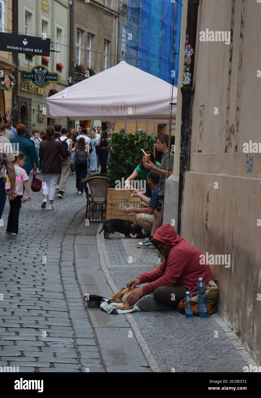 Ein Obdachloser sitzt auf einer Straße in Begleitung eines Hundes. Stockfoto