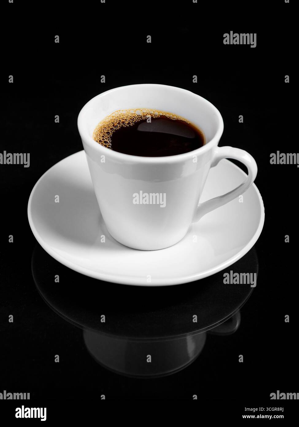 Eine dampfende Tasse dunkel gerösteten Kaffee steht auf einer weißen Untertasse vor einem kräftig schwarzen Hintergrund. Stockfoto