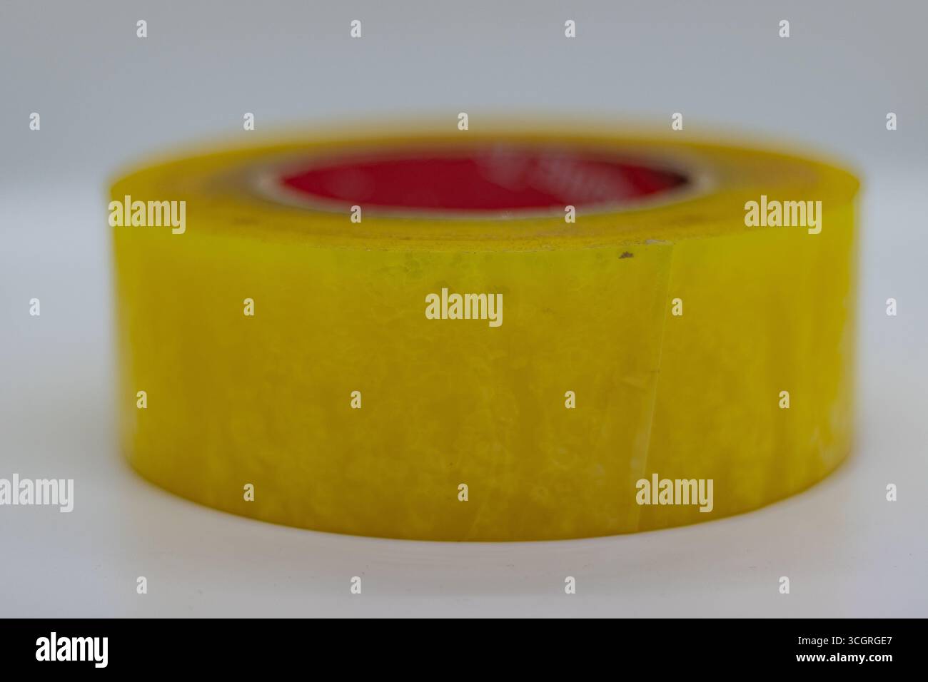 Langlebige gelbe Verpackungsbandrolle mit Kartonkern auf weißer Studiooberfläche Stockfoto