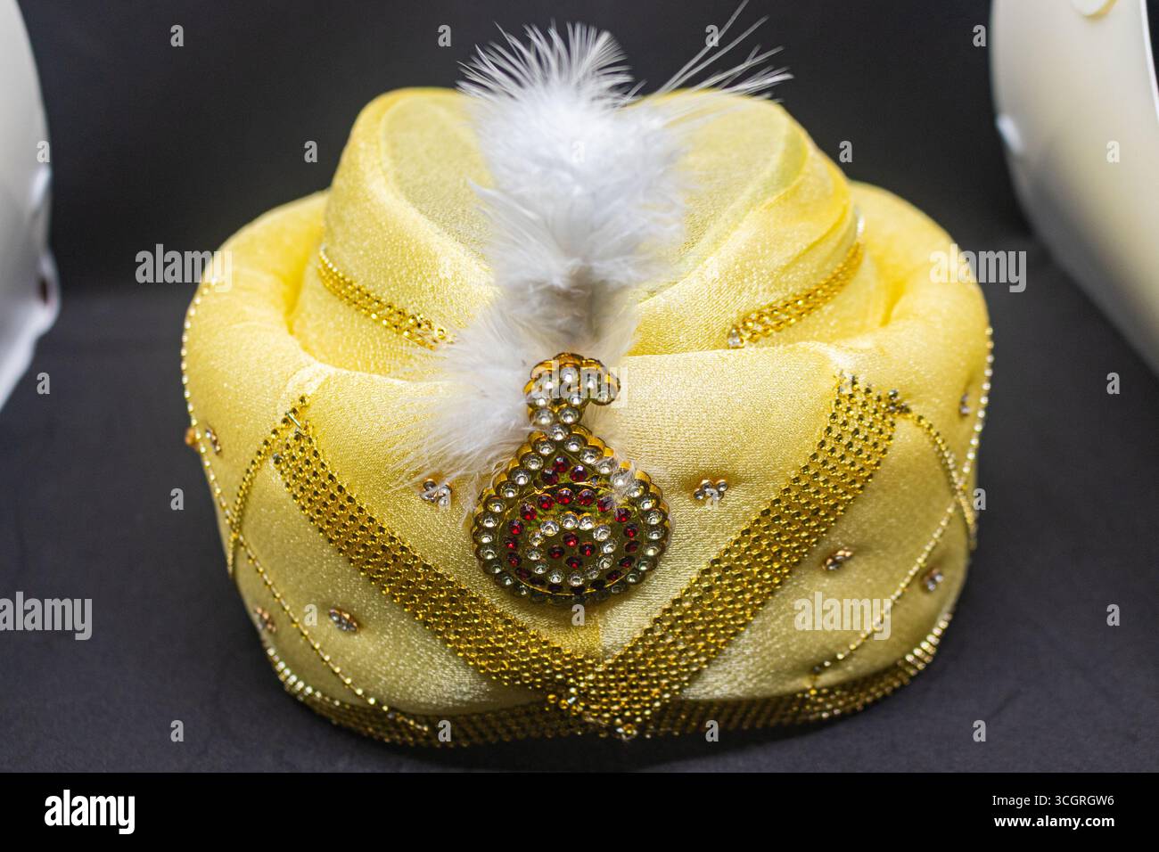 Elegante goldene Hochzeit Turban mit Feder auf dunklem Hintergrund Stockfoto