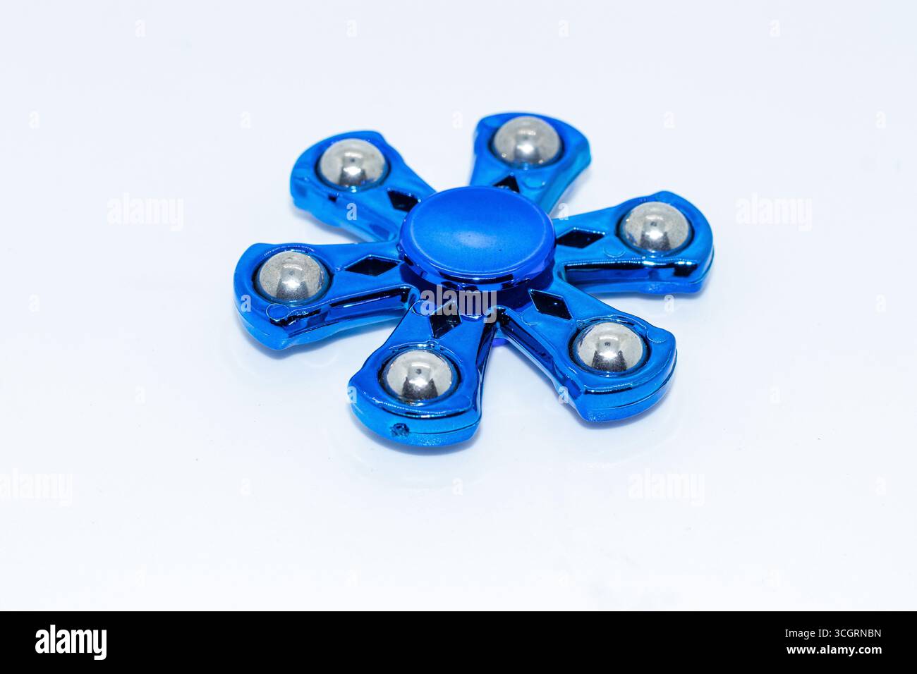 Glänzender blauer Metall zappeln Spinner mit Stahllagern auf weißem Hintergrund Stockfoto