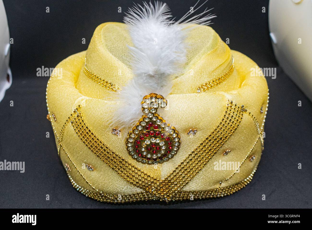 Glänzende goldene indische Hochzeitskopfbekleidung mit weißer Feder Stockfoto