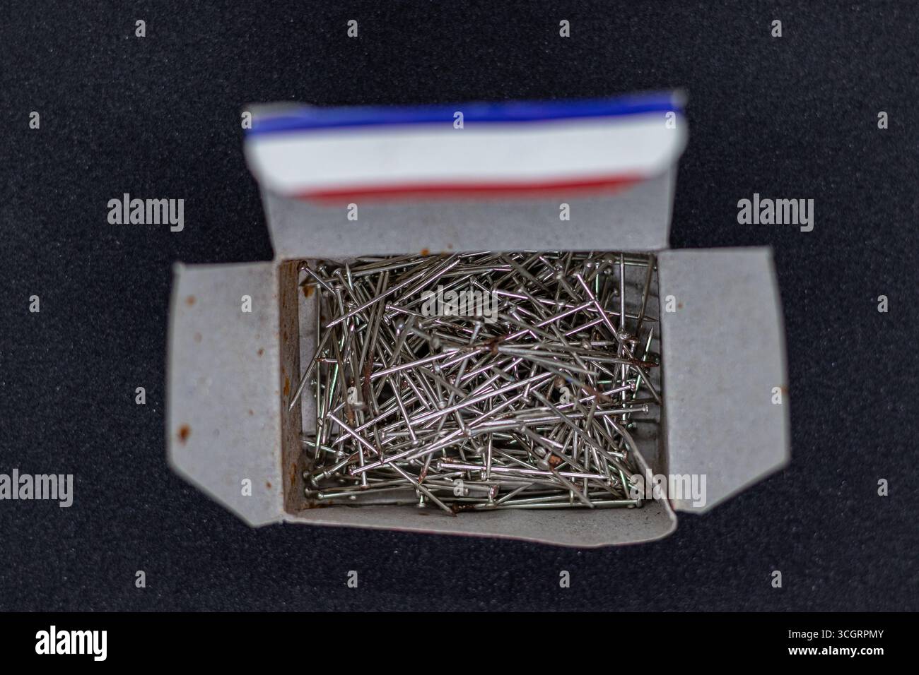 Gebrauchte silberne Daumentaster in Red Box auf strukturiertem dunklem Hintergrund Stockfoto