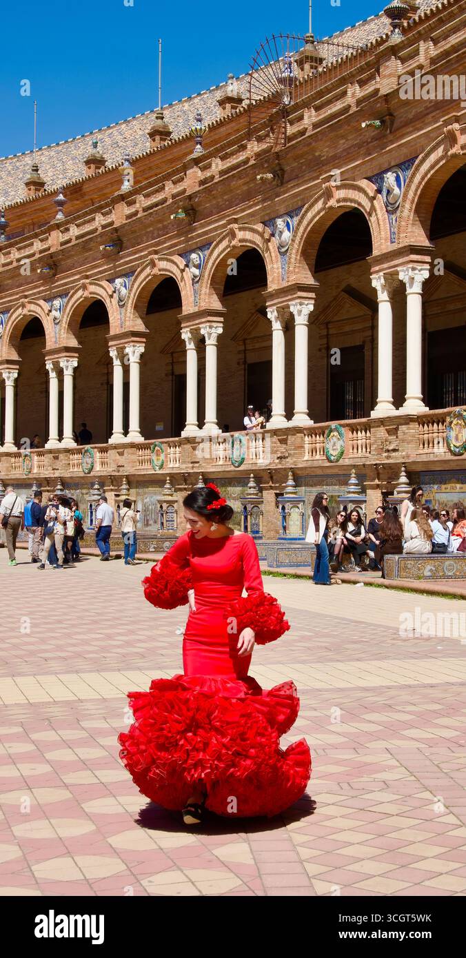 Junge Frau, die ein traditionelles rotes Flamenco-Kleid und passende rote Blumen in einem Haargutt trägt Plaza de España Sevilla Andalusien Spanien Europa Stockfoto